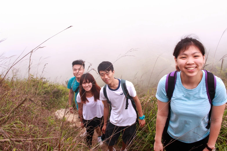 four people standing in the tall grass on a trail