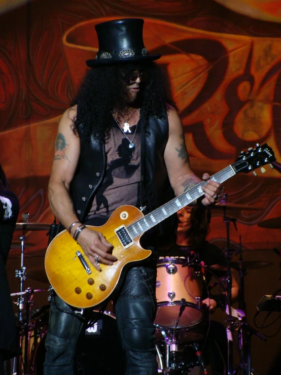 a man with a long black hat and beard playing a yellow guitar