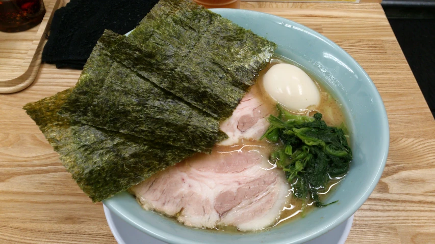 a bowl of ramen with meat, broccoli and an egg