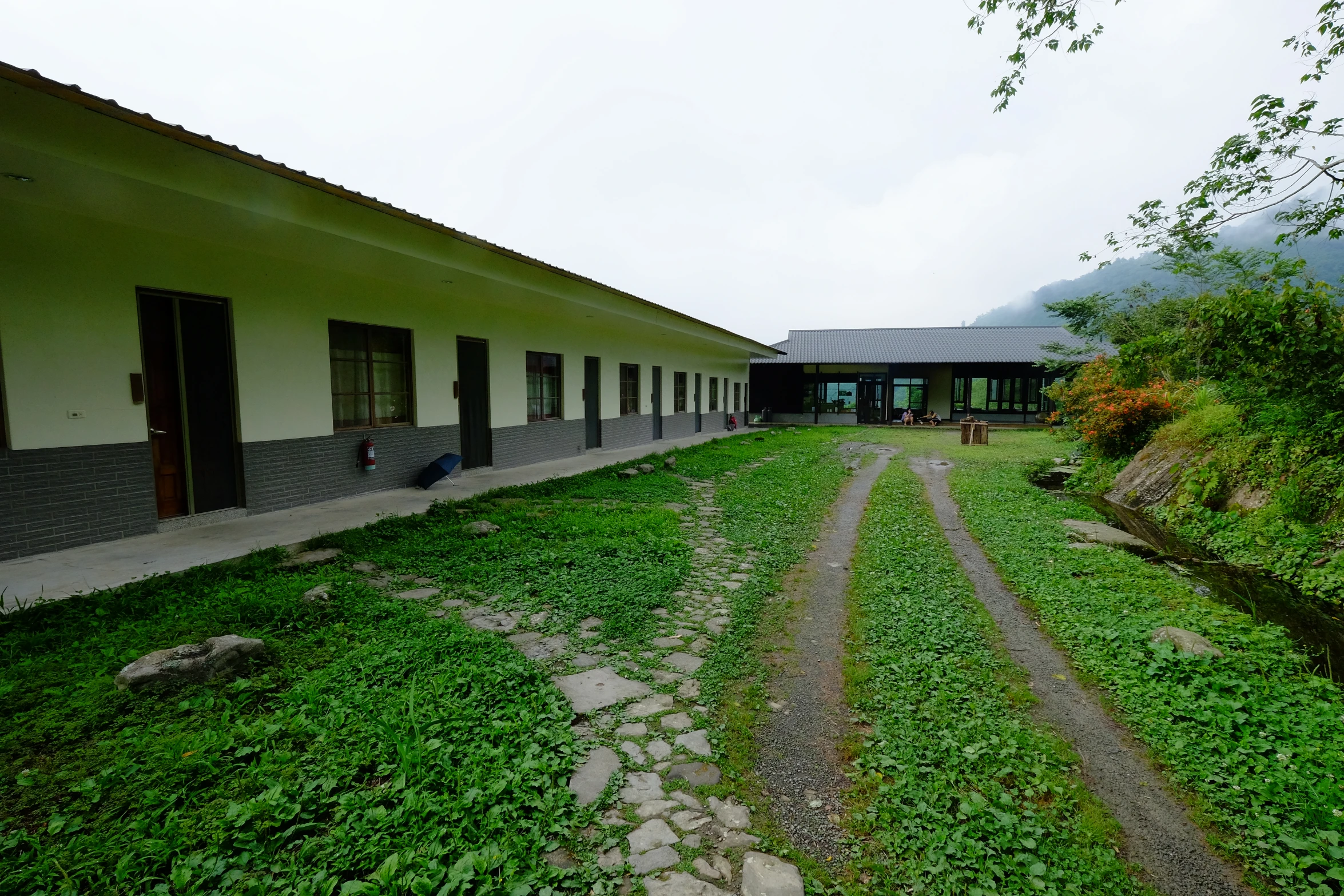 two buildings in an outdoor area with a green lawn and stone walkway