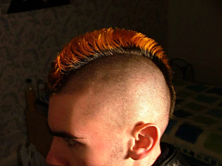 a bald man with orange mohawk has spiked hair