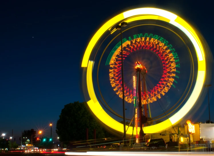 the large ferris wheel is colorful in the night sky