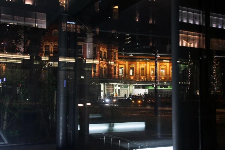 city lights reflected in window of a large building at night