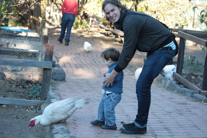 a woman feeding a white goose at the zoo