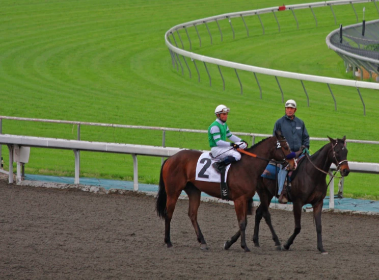 a man and woman on horses near the track