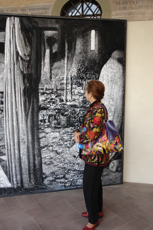 the woman stands near a painting that looks like a huge painting