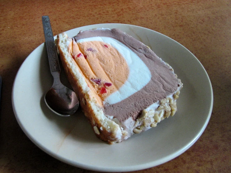 a slice of cake with frosting and a spoon on the plate