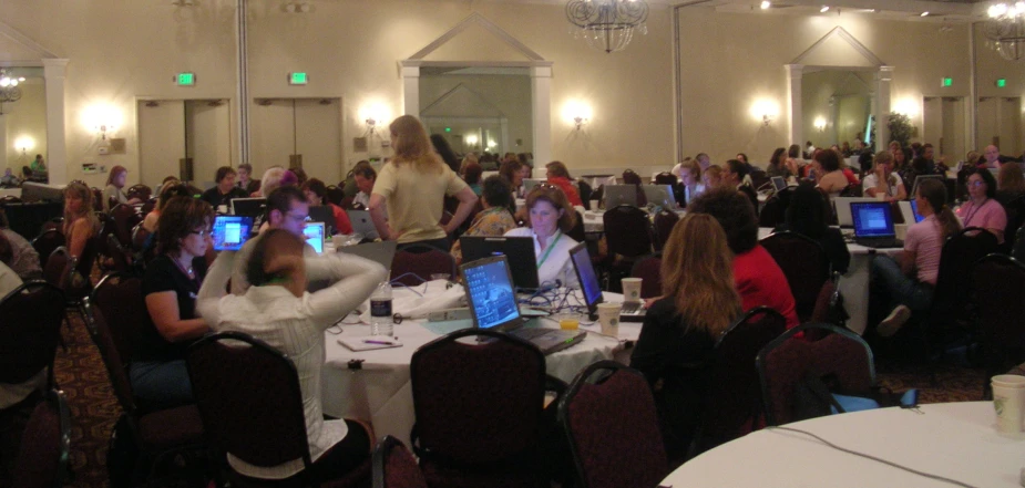 many people with their laptops are sitting at tables