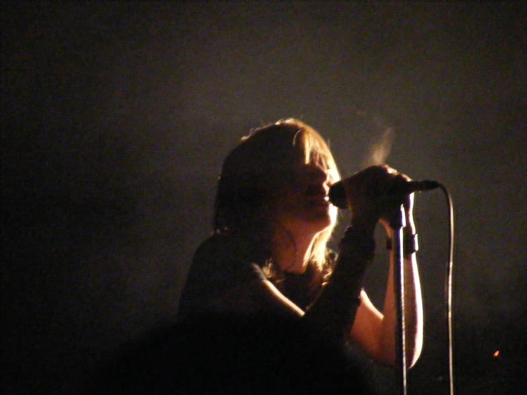 the woman is holding a microphone up while singing