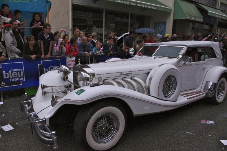 this is a vintage white car driving down the street