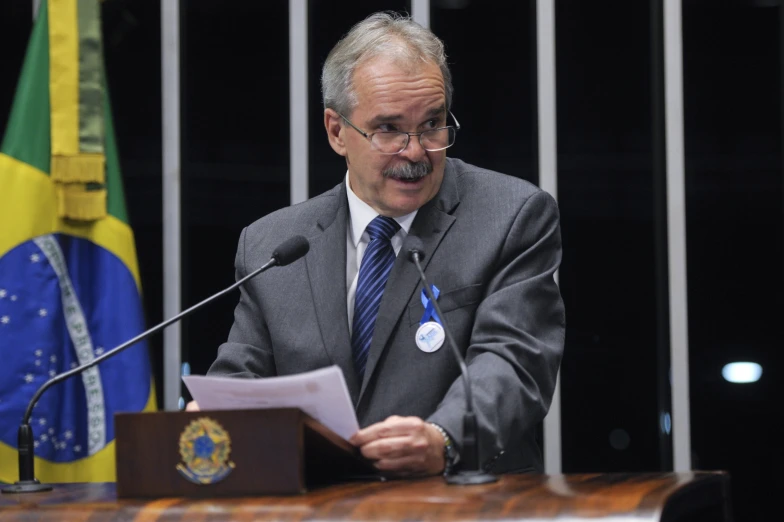 a man with a mustache and glasses gives a speech