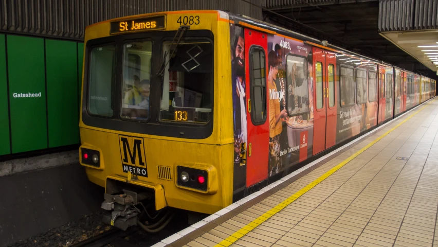 a red and yellow train on tracks inside of a station