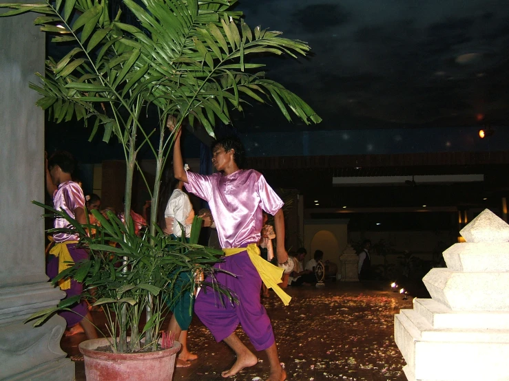 a man in a purple outfit holds a banana on top of a tree