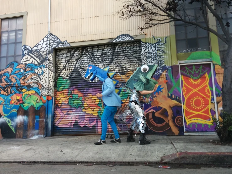 two people are standing outside near a graffiti wall