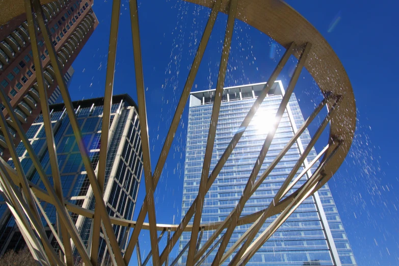 an abstract structure in front of skyscrs with sun shining down