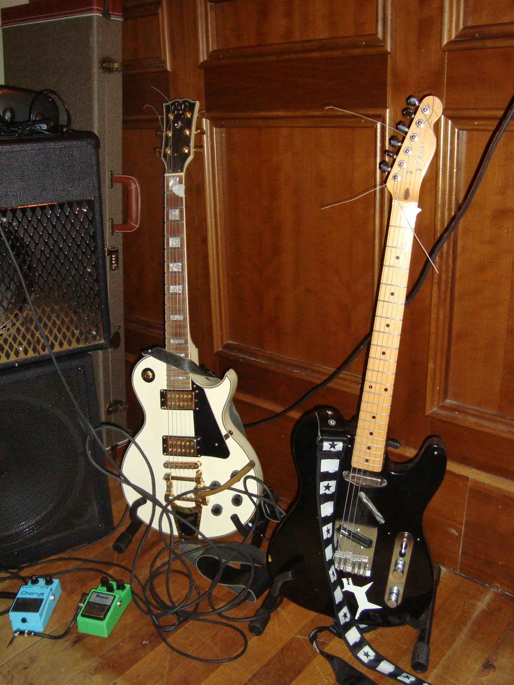 a couple of guitars and an amp on a hard wood floor