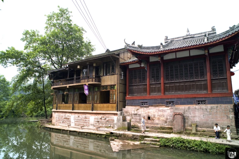 people stand by the water in front of a building with windows