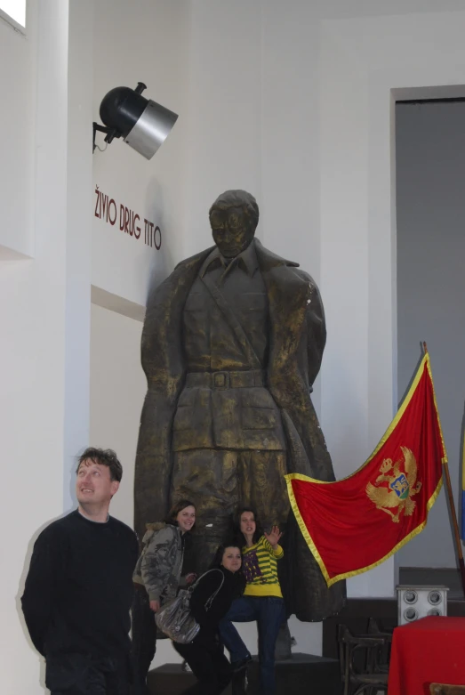 people pose in front of a statue with a flag