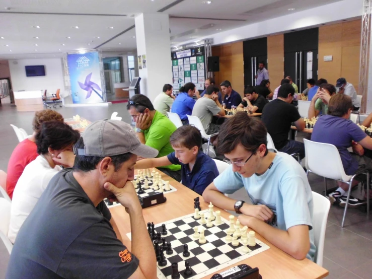 a bunch of guys are playing chess at a table