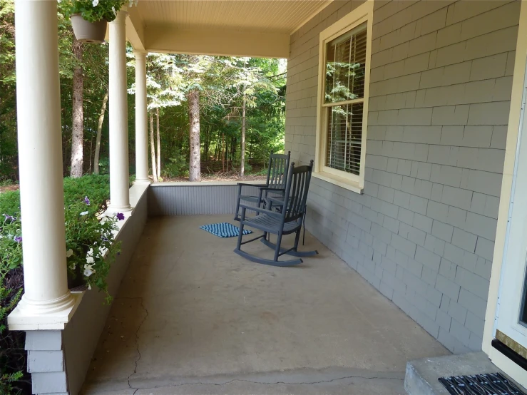 the porch has rocking chairs and flowers by it