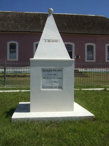 a white monument sits outside of a large building