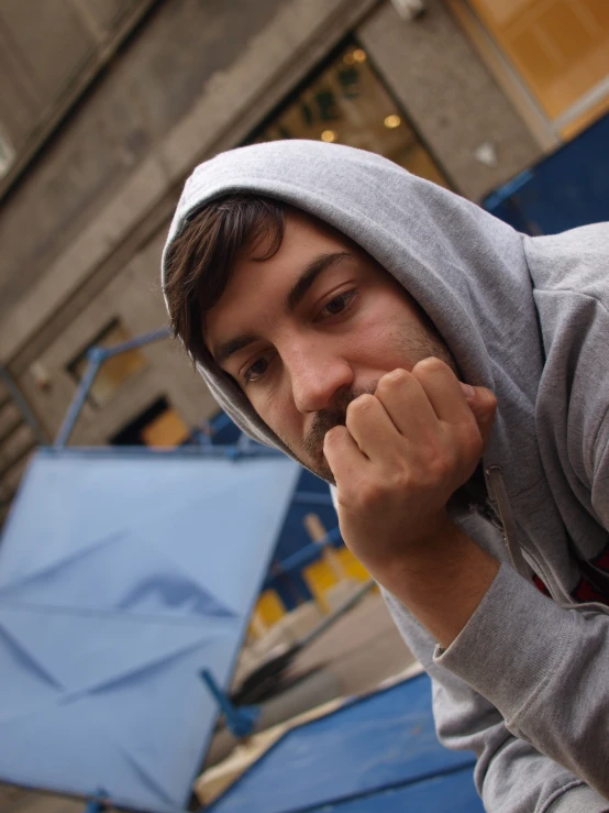 a man in a grey hoodie covering his mouth