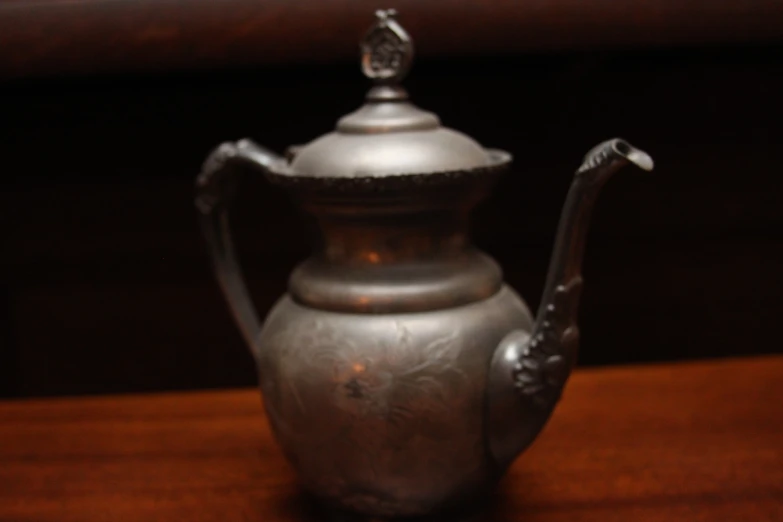 an antique teapot is on a wooden table