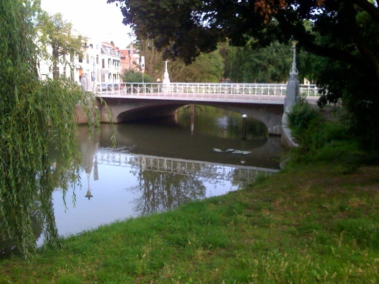 a bridge over a river, surrounded by grass and trees