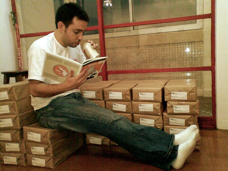 a man sitting on top of a pile of boxes with a book