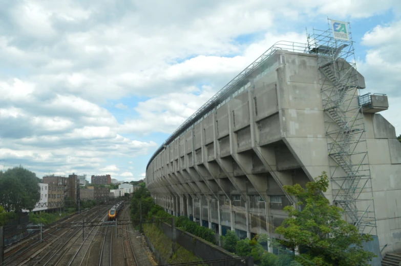 there is a large concrete building that has a train track nearby