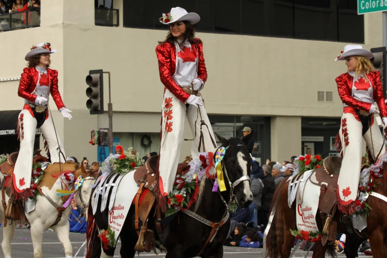 people riding horses in the street with flags and hats on