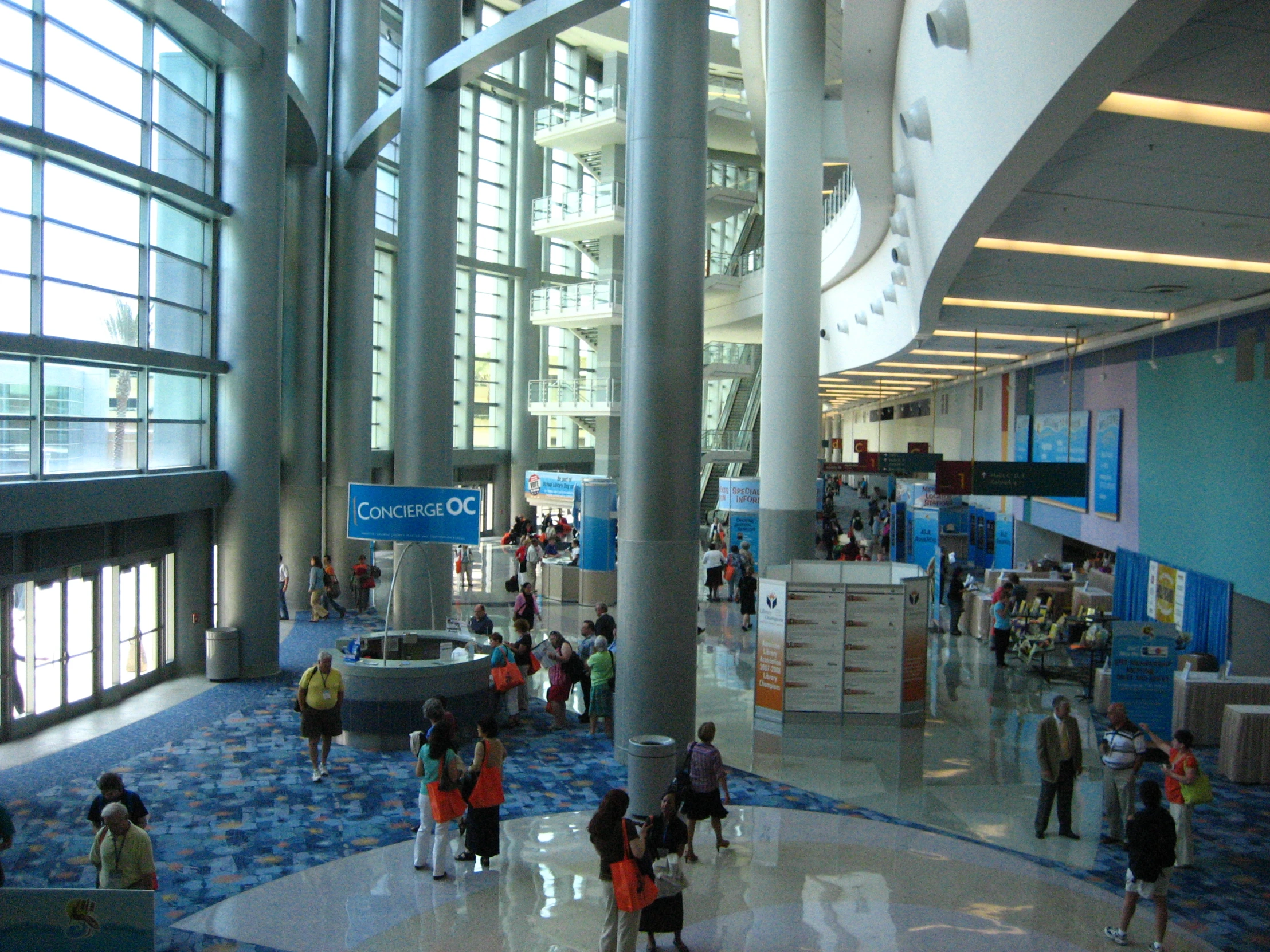 a lobby with glass doors and pillars full of people