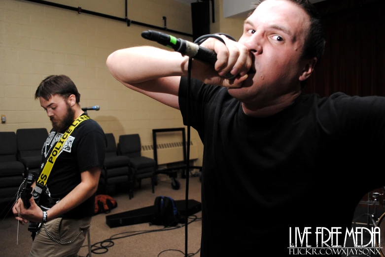 two men singing into microphones with one holding a microphone up to his head