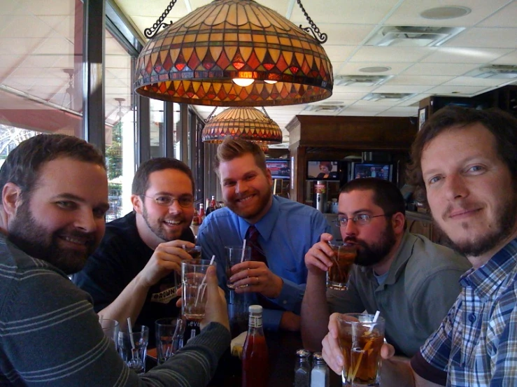 a group of men are toasting at the bar