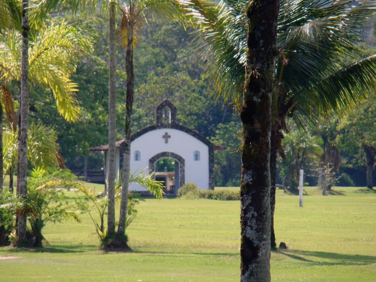 a building sits among the trees on the side of a grassy field