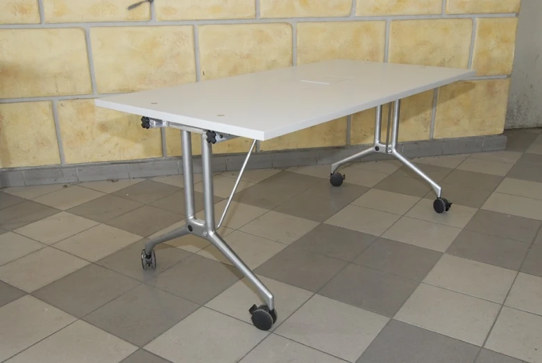 a white table with a metal wheels in front of a brick wall