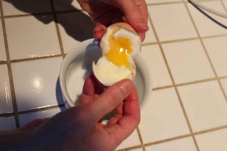 someone is peeling an egg shell into a bowl