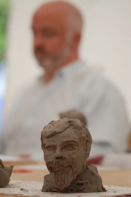 an older man is casting clay sculptures on the table