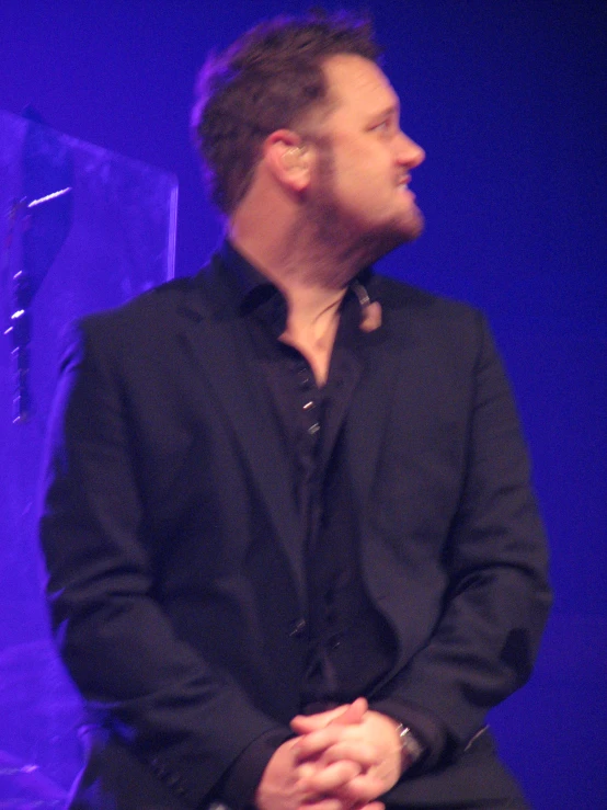 a man standing on stage at a concert looking to his left