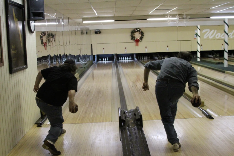 two men riding down a bowling alley next to each other