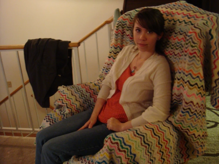 a woman sitting on a bed covered in a blanket