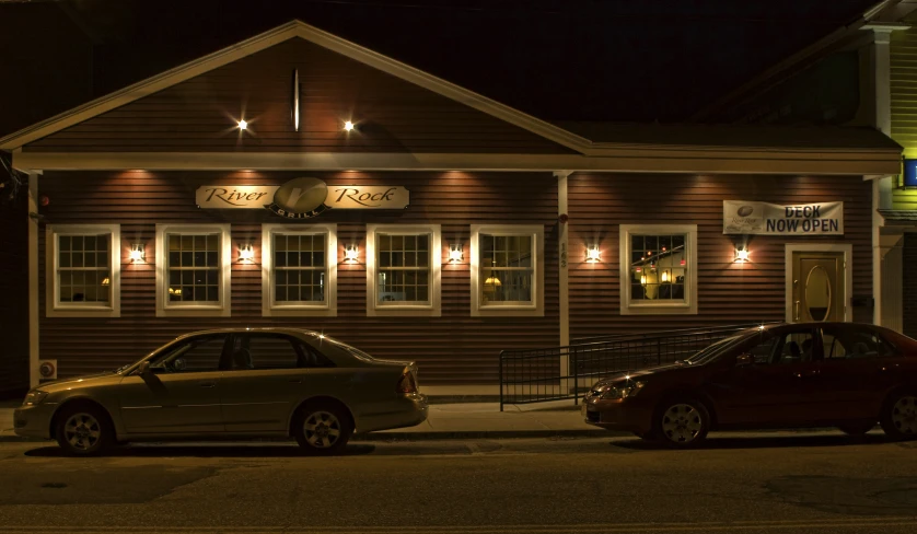 two cars outside of a small building on the corner of a street