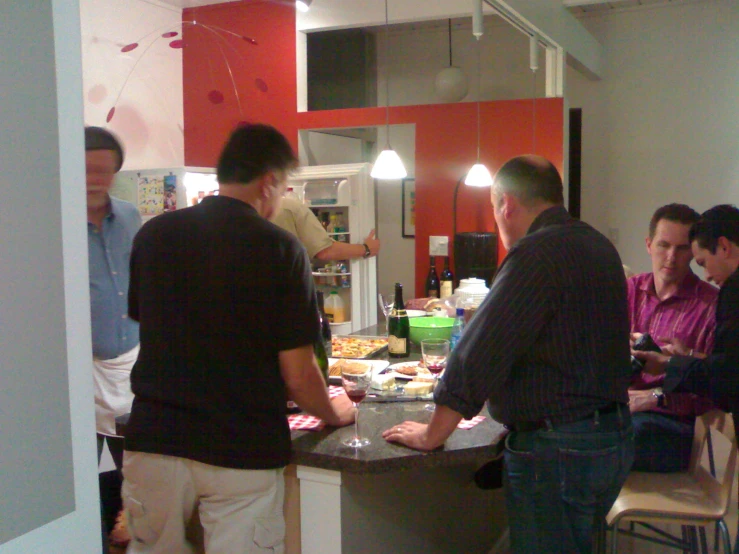 group of men standing around counter in indoor kitchen