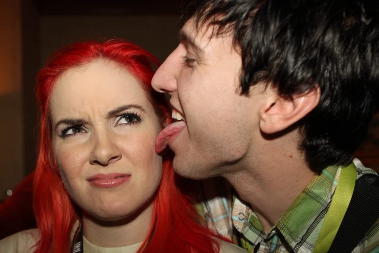 a beautiful redhead woman licking a man's lips