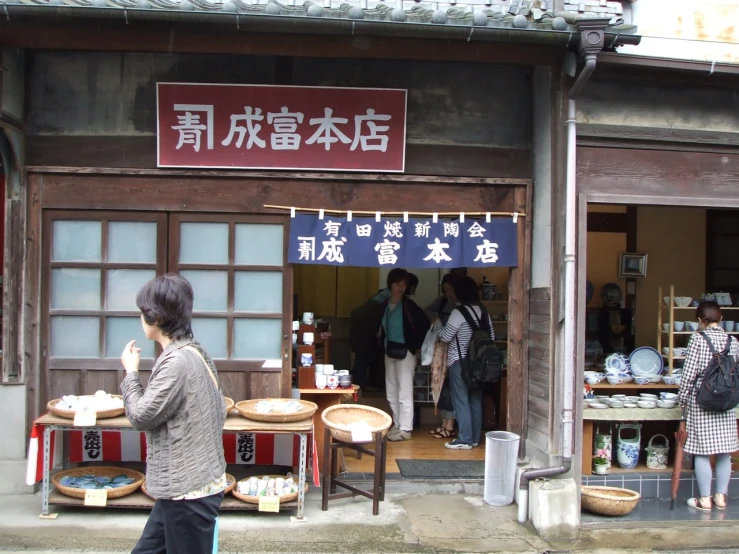 people waiting outside of an asian shop, with asian writing on the sign