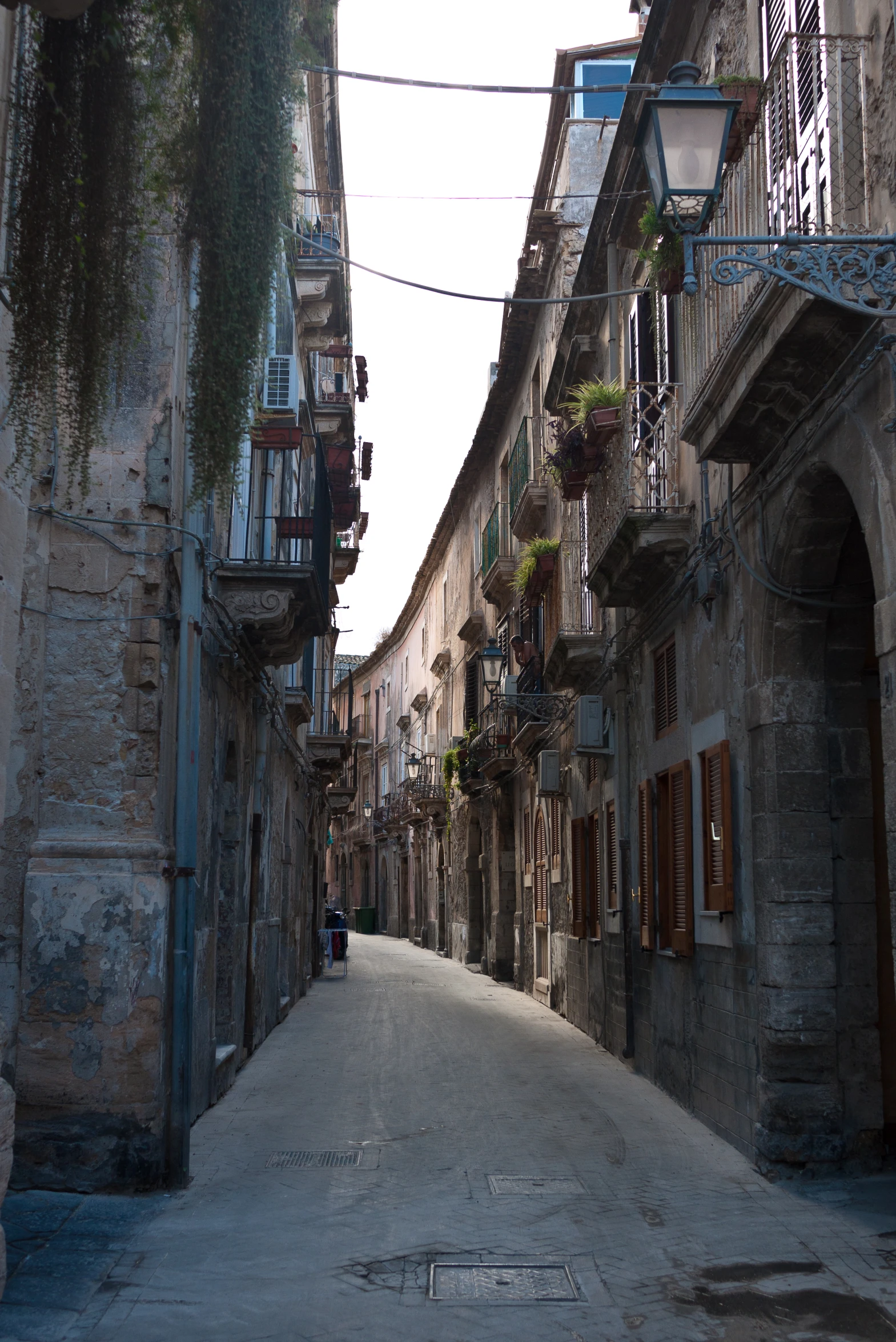 an alleyway lined with buildings and pots full of flowers