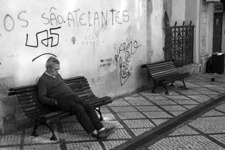 an elderly man sitting on a bench in front of a building