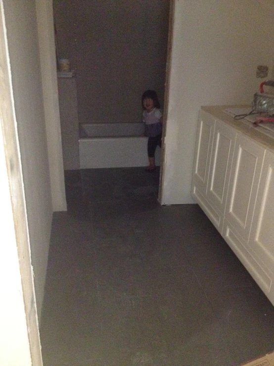 a small child in the middle of an empty bathroom