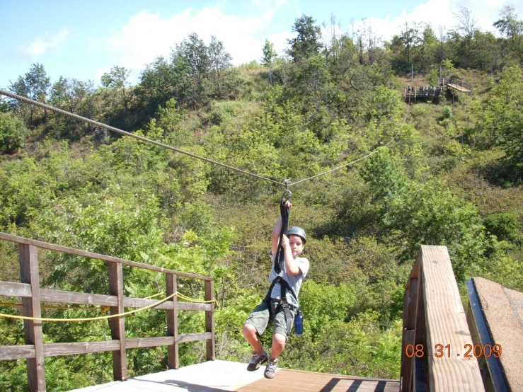 a person on a platform holds onto a rope over water