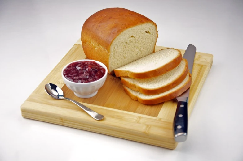 a loaf of bread, er, and cranberry jam are sitting on a  board